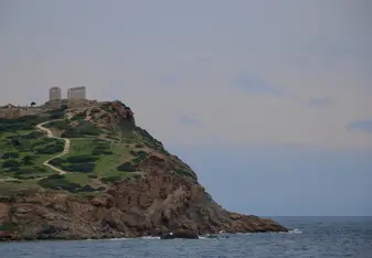 Cape Sounion is the Temple of Poseidon. It is an ancient ruin with tall columns. It lies on top of a large cliff right on the water.