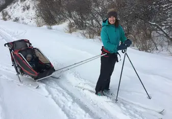 a woman on skis towing a baby in a sled