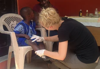 Public Health intern in Ghana treating a child for a minor wound
