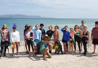 Projects Abroad Diving Conservation Team poses in front of crystal blue ocean survey site