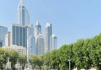 Students on the green AUD campus with the Dubai skyline in the background.