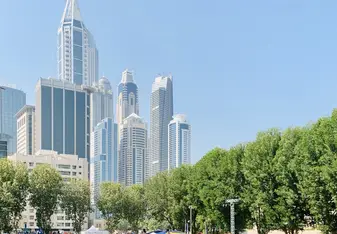 Students on the green AUD campus with the Dubai skyline in the background.