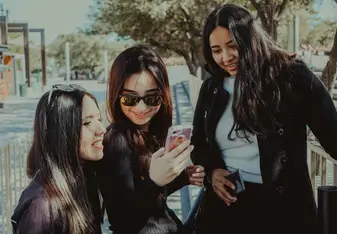 Three women looking at a cell phone.