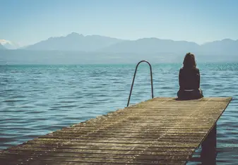 Woman sitting on a dock near the water.