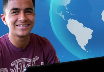 young male smiling at computer desk with virtual world in background
