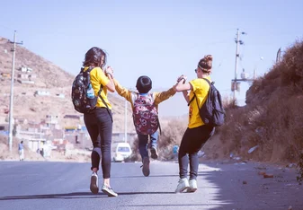 two volunteers and one of the kids jumping on the street