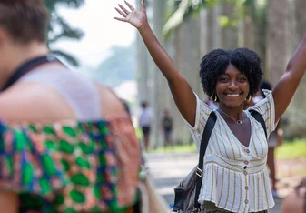 A smiling student with her hands in the air