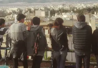 A group of students lined up a long a fence look at the view before them in Athens, Greece