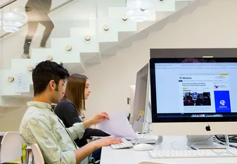 Two students sit at desktop computers