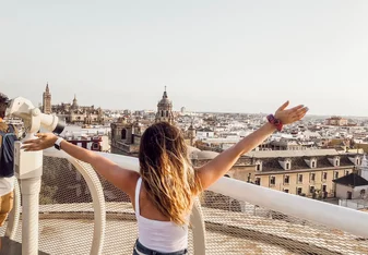 best countries to study creative writing Person standing on balcony with hands up looking at city