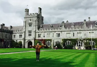 Student with arms stretched out in front of a university building