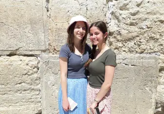 Two women stand in front of the Western Wall