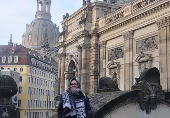 Kania Putri P wearing a scarf and glasses smiling