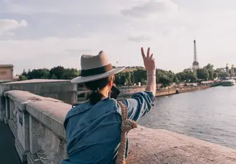 A woman with her back to the camera making a peace sign in the air.