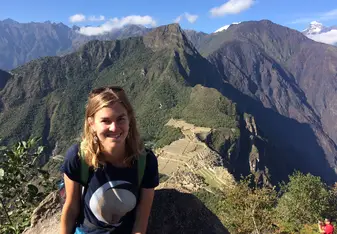 Ellie at the top of a mountain with ruins and a blue sky behind her