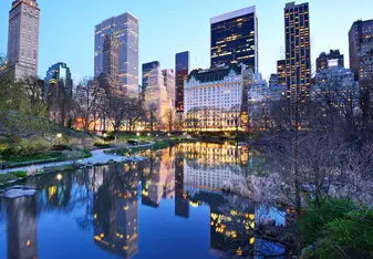 A city landscape with a blue reflective lake