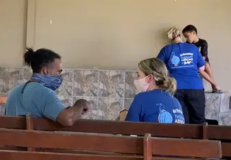 Two Therapy Abroad volunteers wearing blue company shirts helping two locals