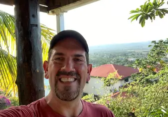 Bob Serianni wearing a red shirt and ball cap smiling