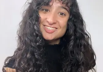 Brianna Dora Costa with curly black hair and brown eyes smiling