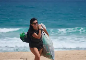 Débora Newlands Souza carrying a bag of trash she picked up off a beach