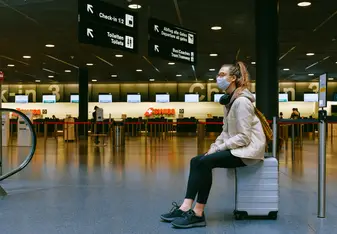 Person sitting on suitcase waiting at airport