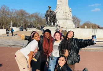 group of students pose in front of monument in london