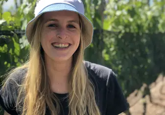 Madison Purnell outside wearing a bucket hat smiling with long blonde hair