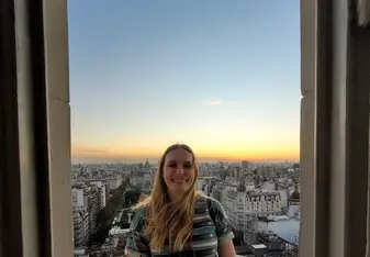 Madison Purnell in an archway with a city behind her during sunset