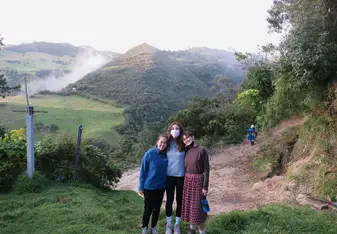 3 students standing in front of hills