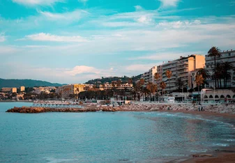 A sunny beach with houses rising along it