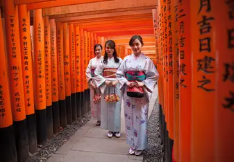 Three women stand in traditional Japanese dress.