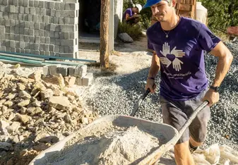 Volunteer moves wheelbarrow full of dirt
