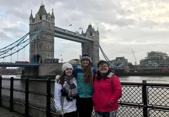 3 travelers smiling in front of bridge