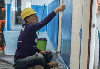 Volunteer painting interior wall