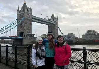 3 travelers smiling in front of bridge