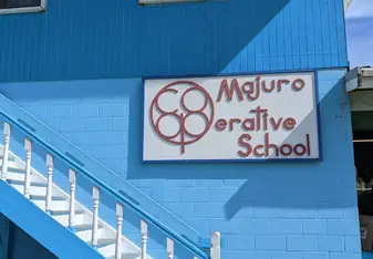 Majuro Cooperative Sign on the side of the office building (blue) above white stairs.