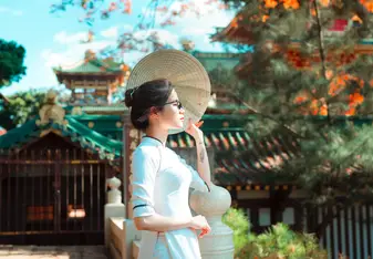 A woman standing to the side with traditional Japanese architecture in the background.