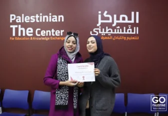 Manar Amro holding a certificate with another person at The Palestinian Center