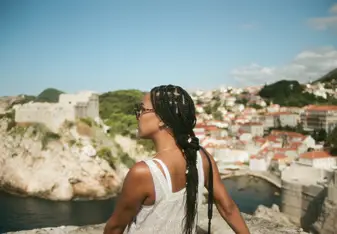 Woman looks to the side with buildings along a bay in front.