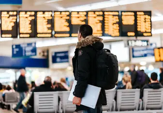 A man looks at a flight board in an airport.