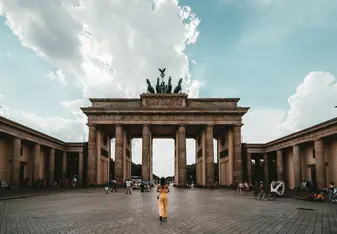 A woman stands in front of large stone gate in Germany.