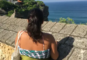 Ashely stands looking over a stone wall in Bali.