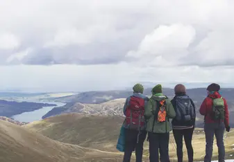 A group wearing backpacks looks at mountains.