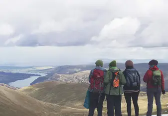 A group wearing backpacks looks at mountains.