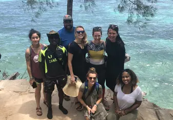 A group of students posing in front of a body of water.