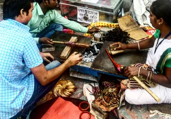 Three people making tools over coals