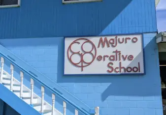 Majuro Cooperative Sign on the side of the office building (blue) above white stairs.