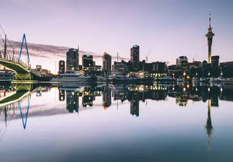 Twilight cityscape of Auckland, New Zealand reflected in water.