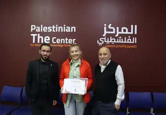 Woman holding a certificate standing between two men in front of a maroon wall