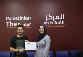 Man and woman holding a certificate in front of a large banner 